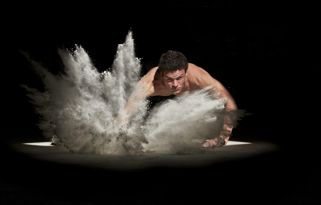 wrestler on the ground splasshing through sand